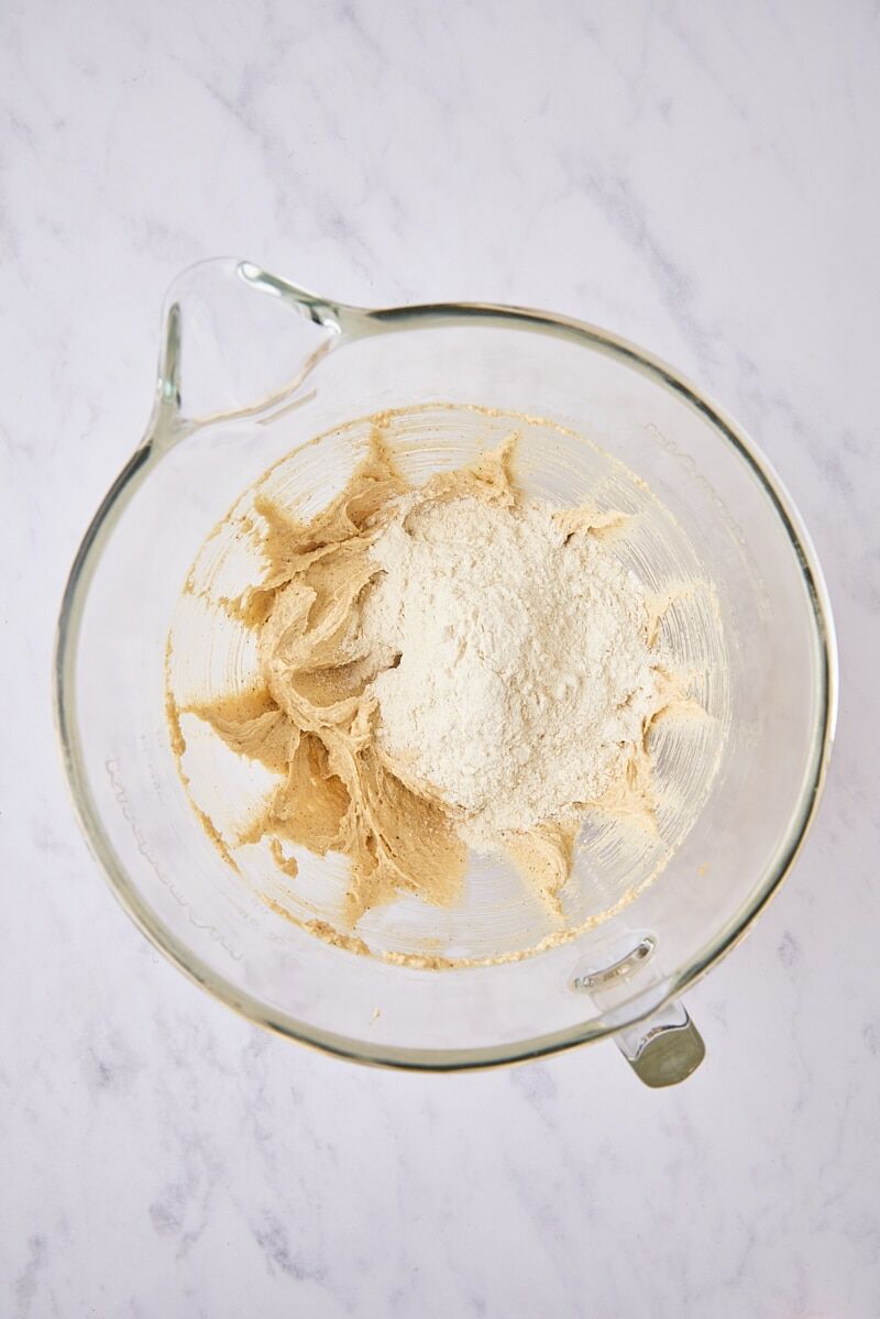 Dry ingredients added to cookie dough in glass mixer bowl