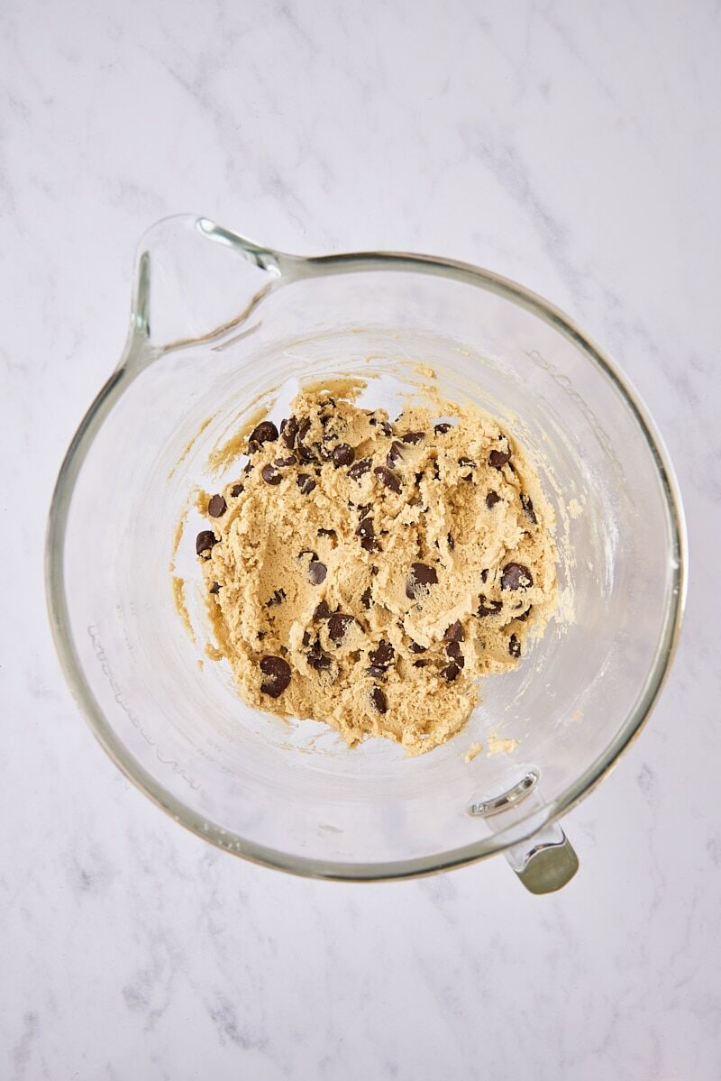 Brown butter chocolate chip cookie dough in glass mixer bowl