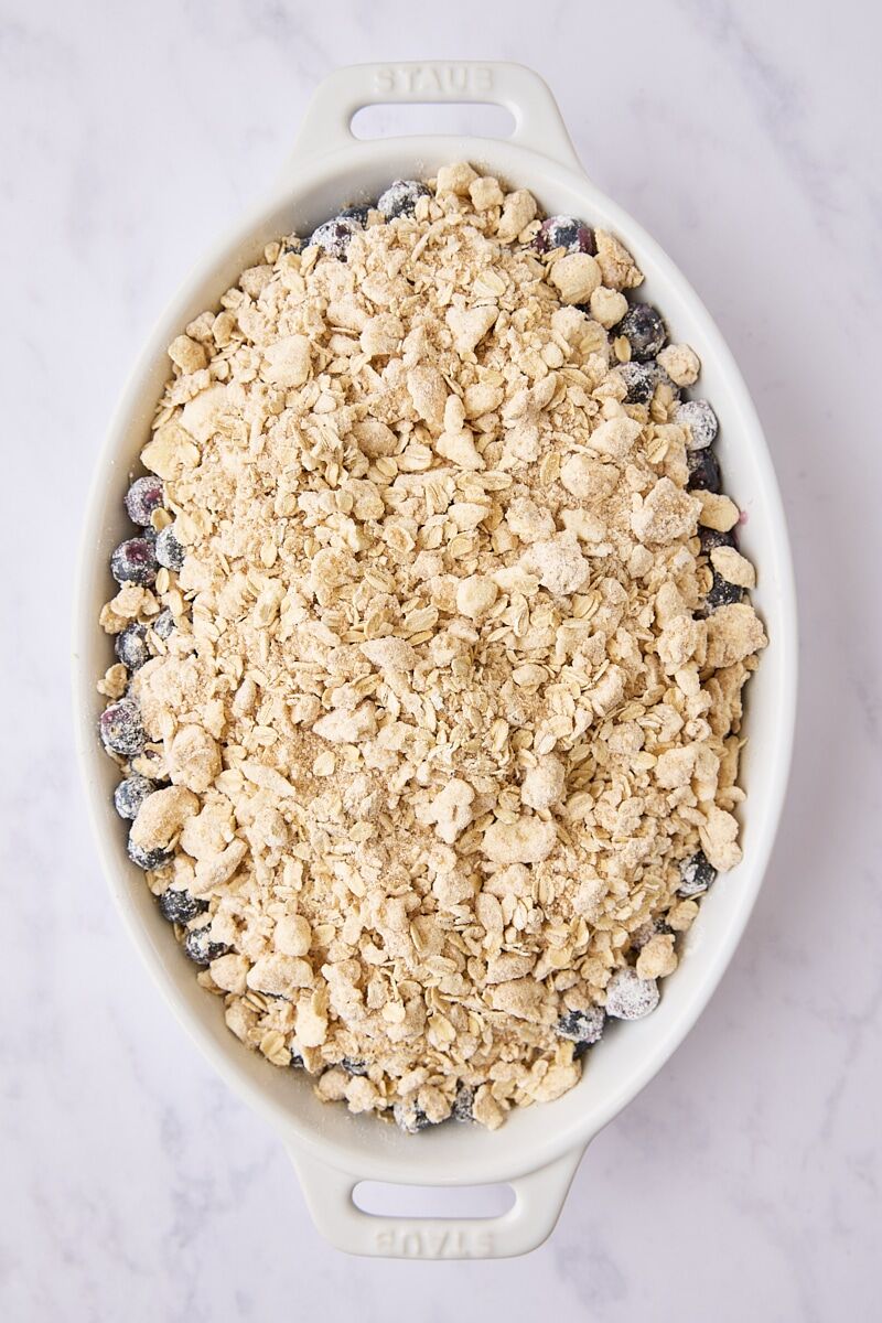 Assembled blueberry crisp in white baking dish