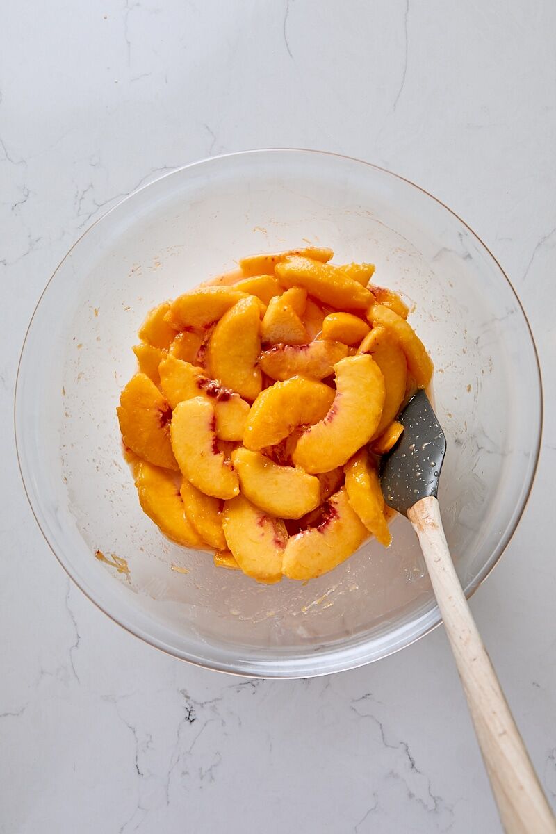 Peach cobbler filling in glass bowl with spatula