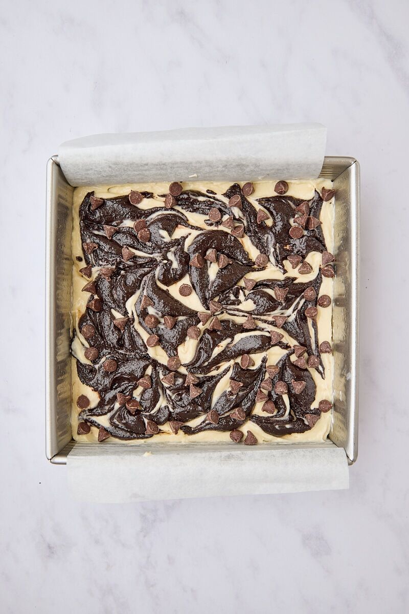 Assembled cream cheese brownies in parchment-lined pan