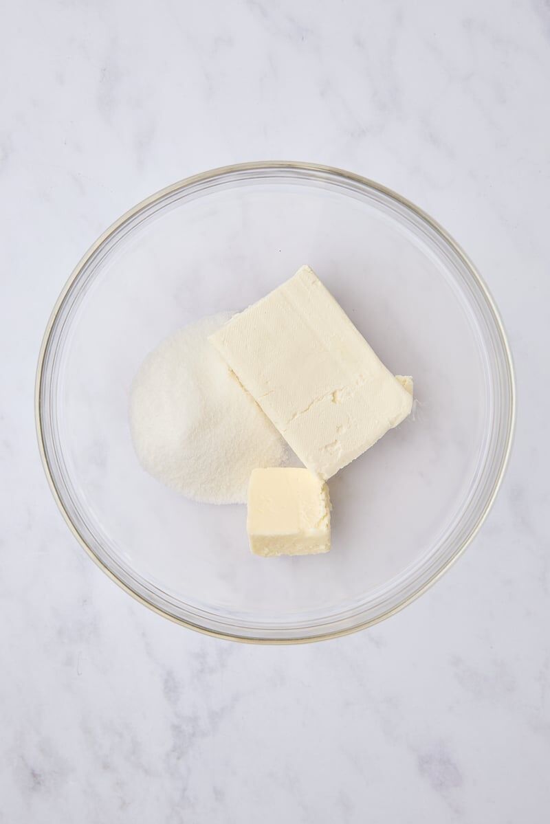 Softened cream cheese, butter, and granulated sugar in glass mixing bowl