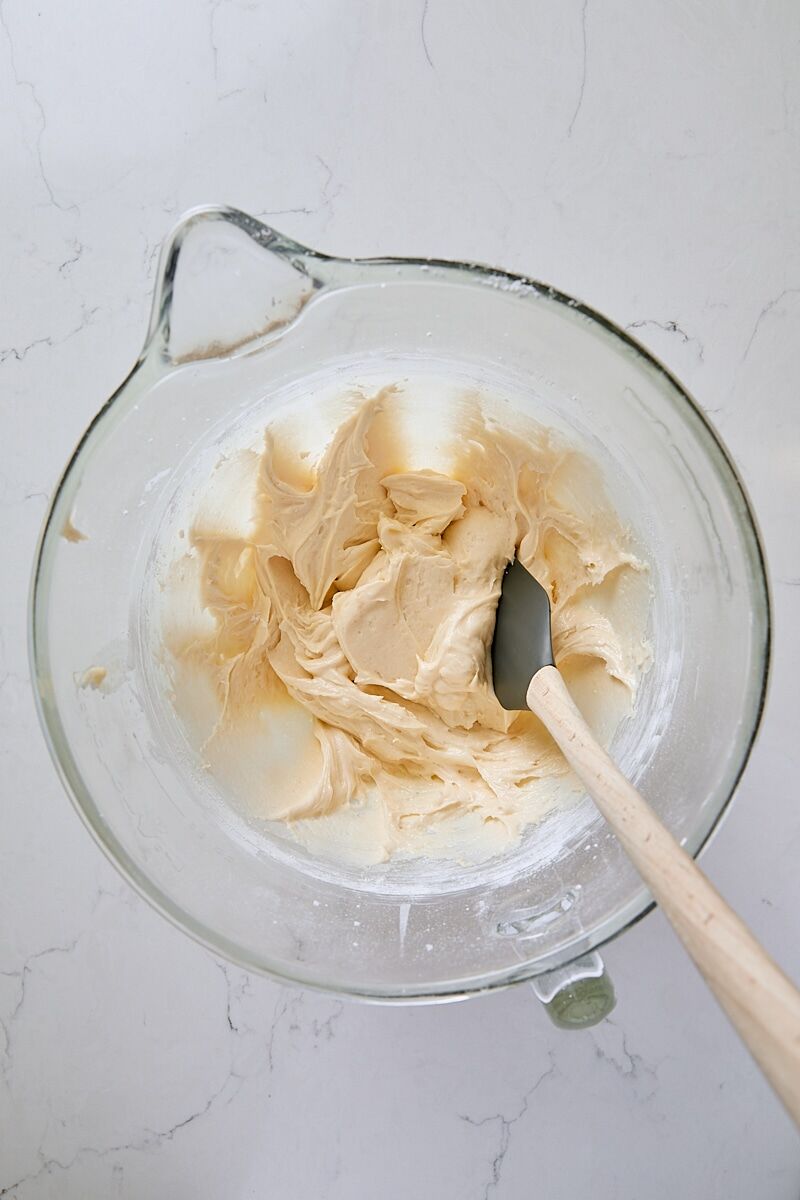 Mixed cake batter in glass mixer bowl with spatula
