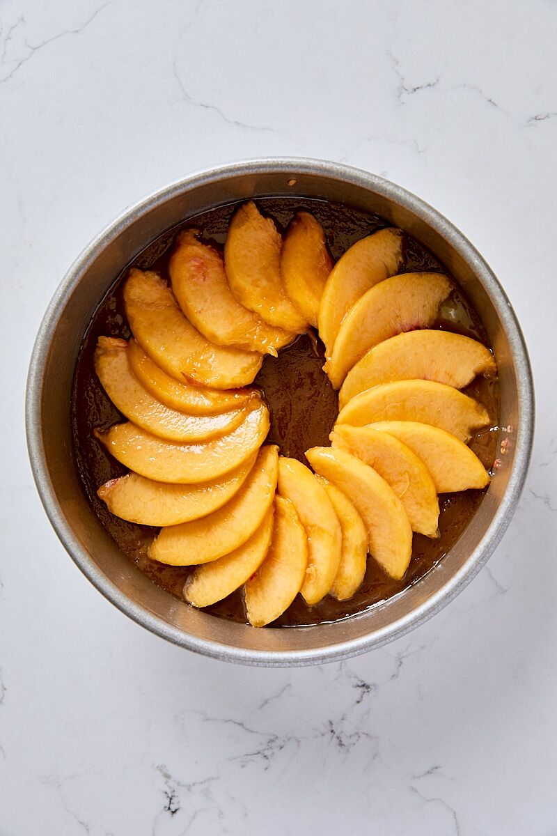 Fresh peach slices layered over brown sugar topping in round cake pan