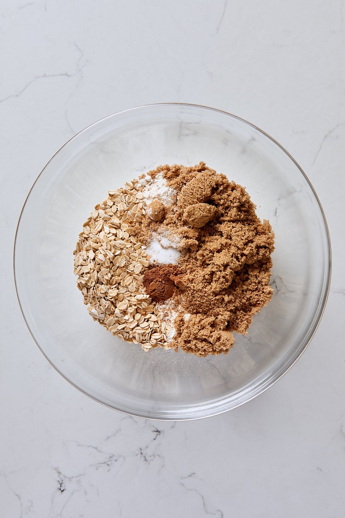 Rolled oats, flour, dark brown sugar, cinnamon, and salt in glass bowl