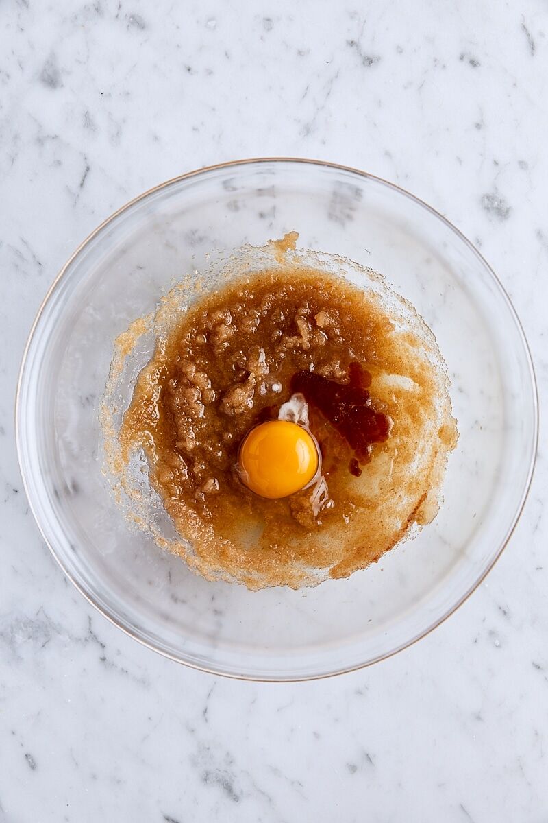 Egg and vanilla added to brown butter mixture in glass bowl