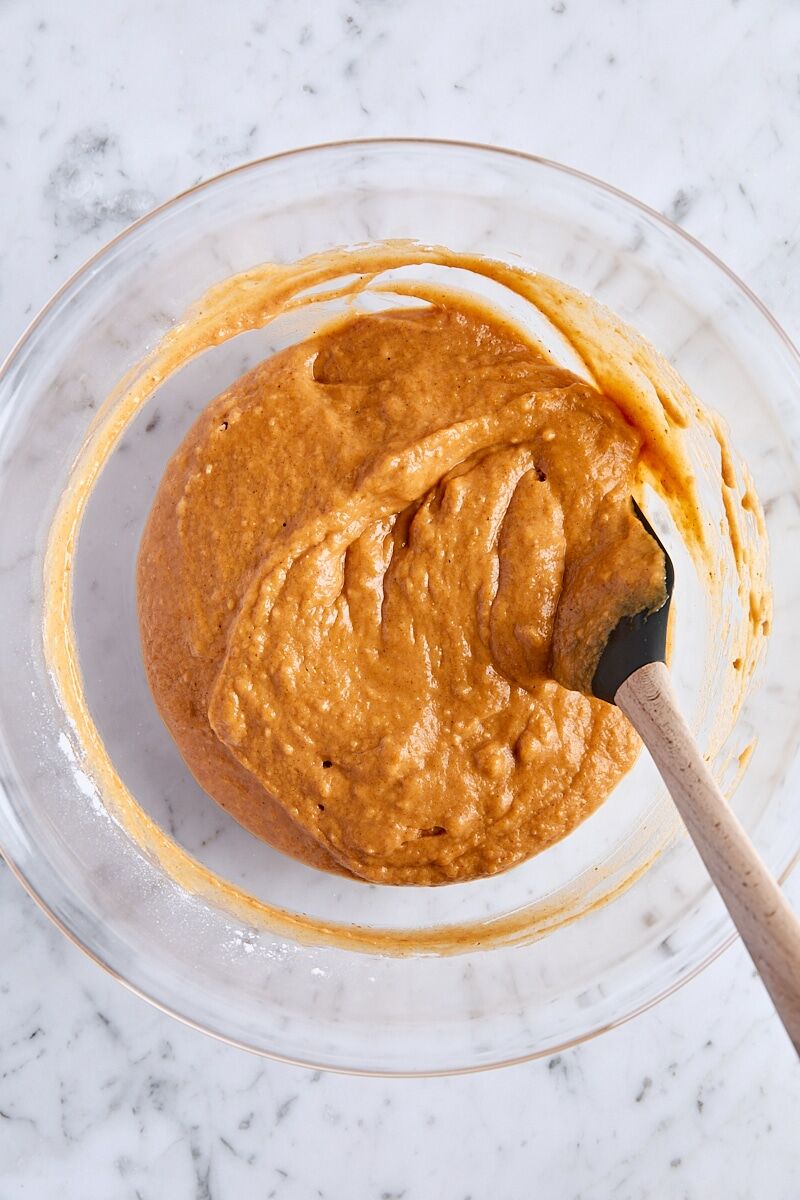 Mixed pumpkin bread batter in large glass bowl with spatula