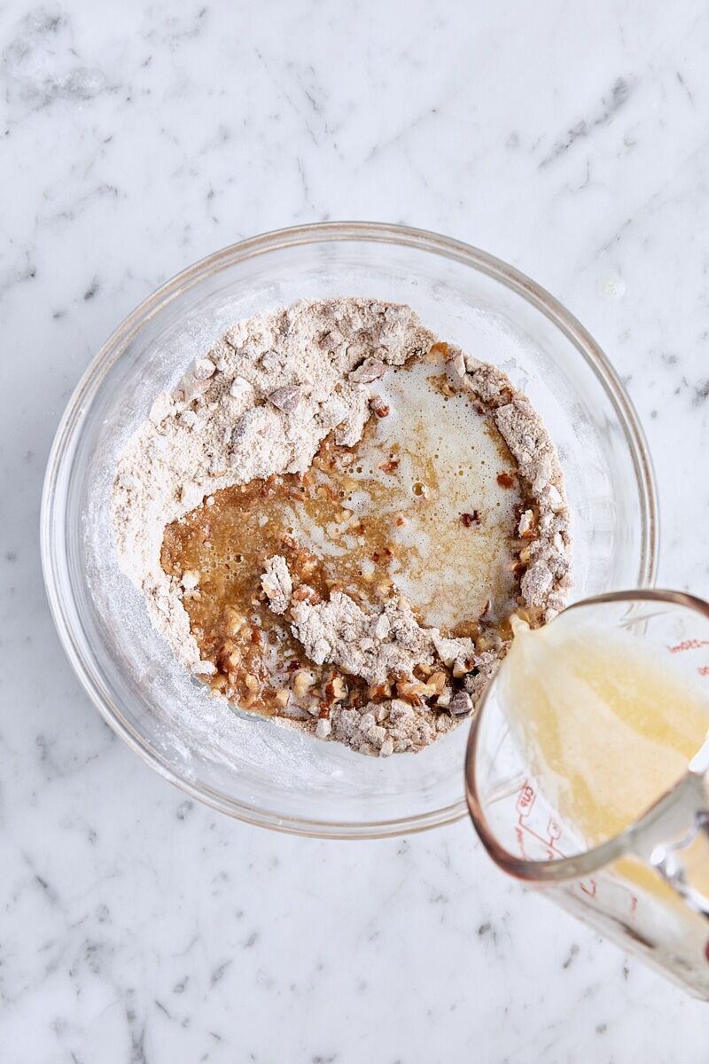 Melted butter added to pecan streusel topping ingredients in glass bowl