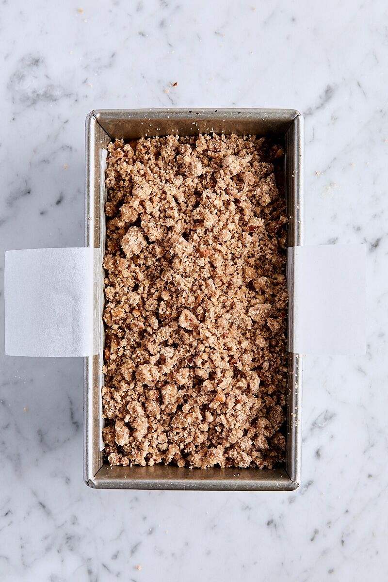 Unbaked streusel-topped pumpkin bread in parchment-lined loaf pan