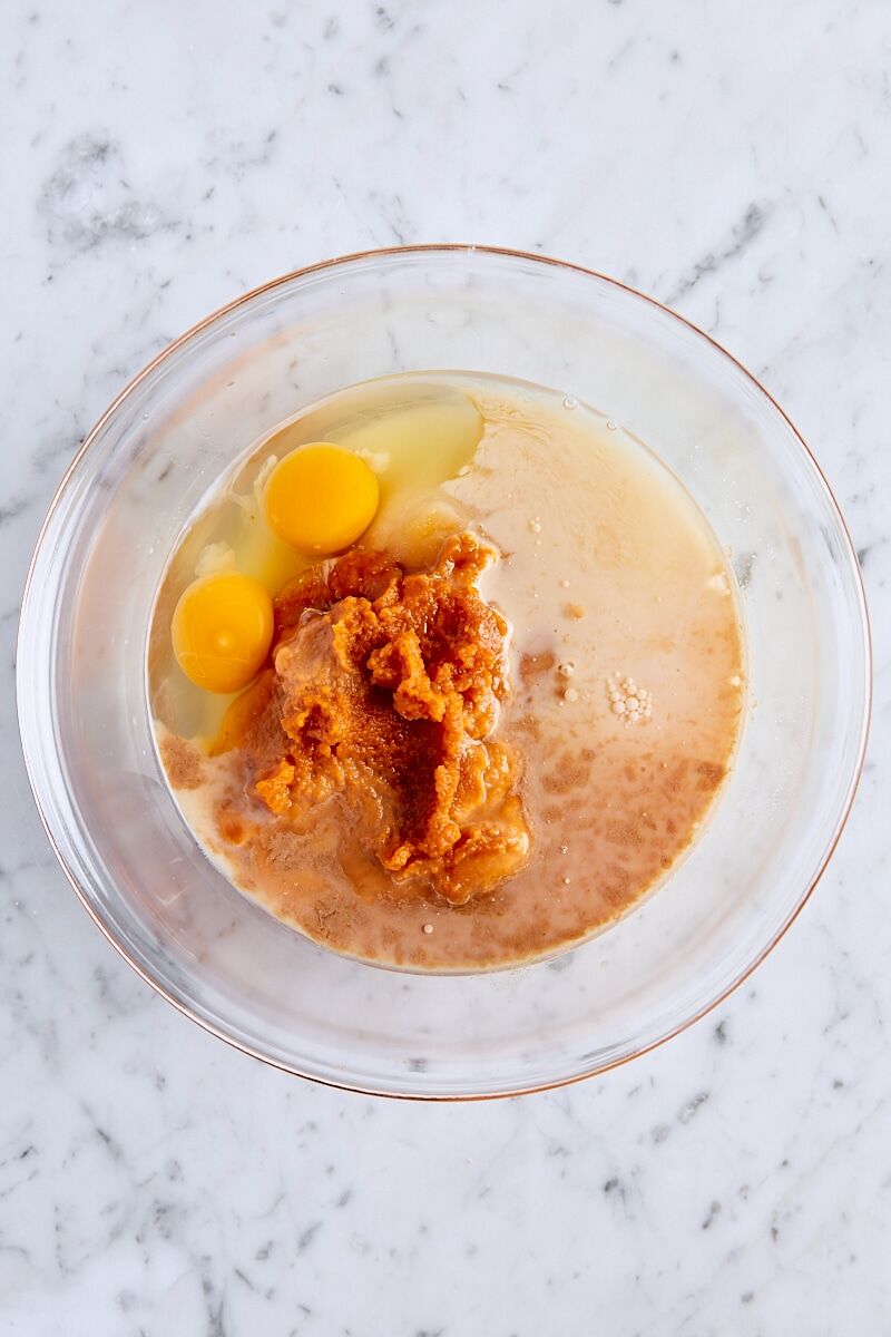 Pure pumpkin puree, granulated sugar, milk, eggs, coconut oil, and vanilla extract in glass bowl