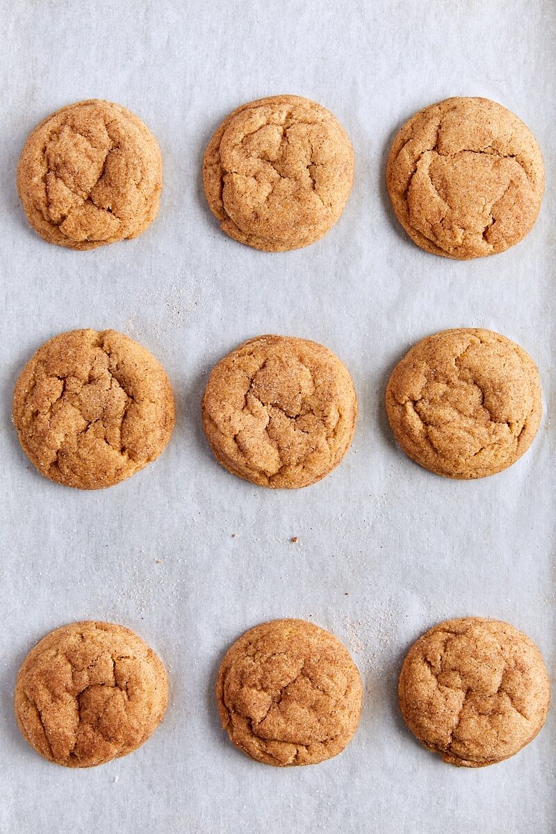 Baked pumpkin snickerdoodle cookies on parchment-lined baking sheet