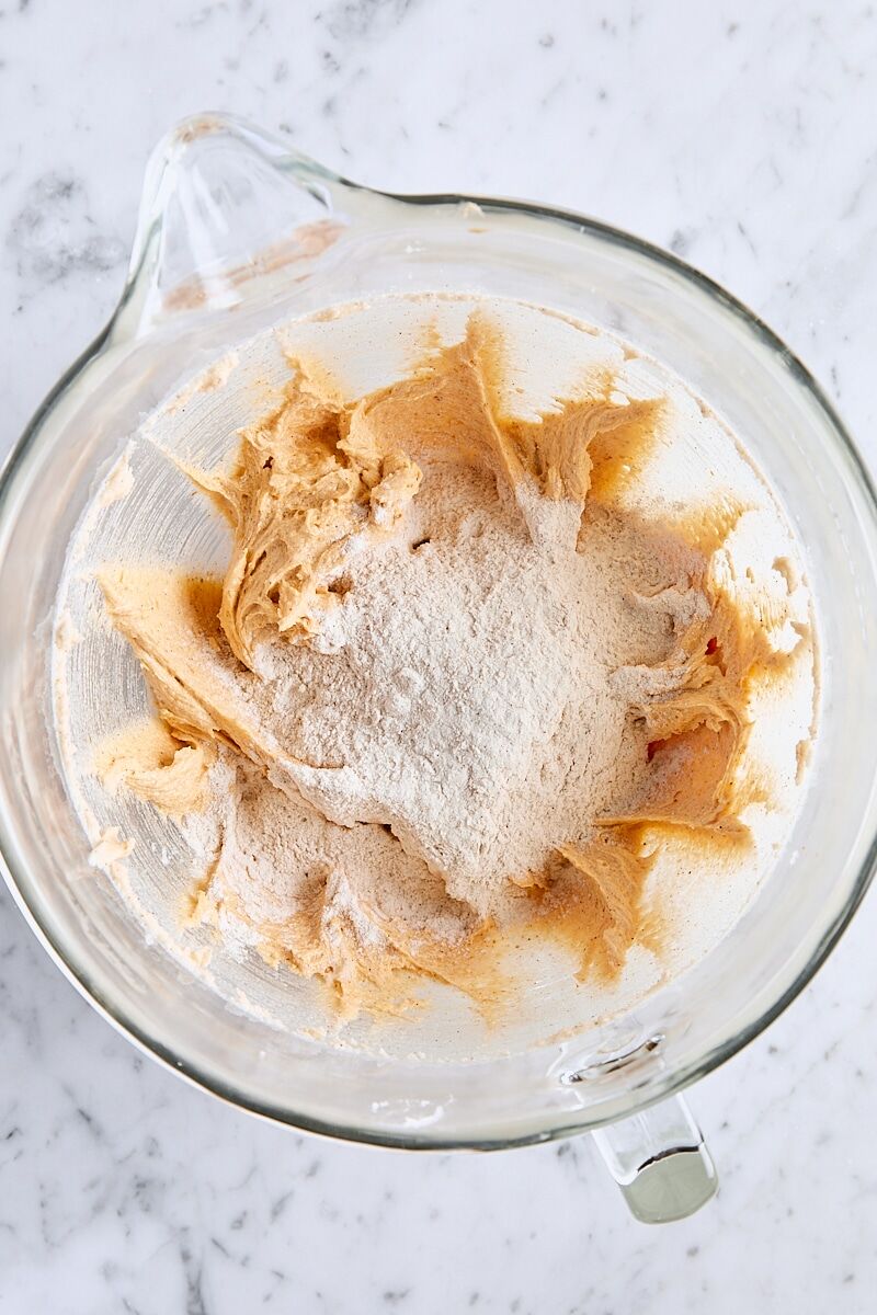 Dry ingredients added to snickerdoodle cookie dough in glass mixing bowl