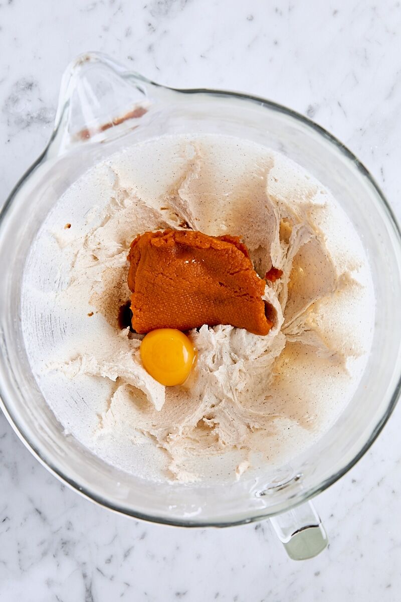 Pumpkin puree, egg yolk, and vanilla added to snickerdoodle dough in glass mixing bowl