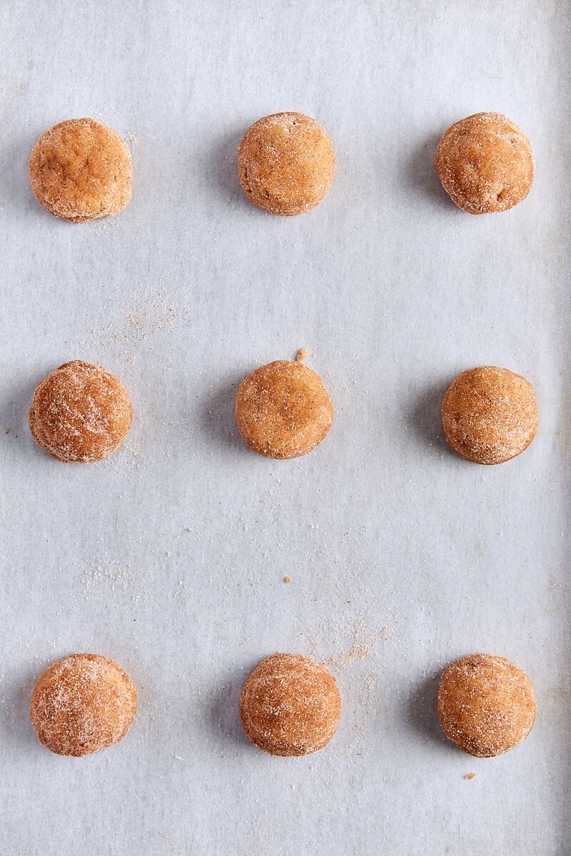Pumpkin snickerdoodle dough balls scooped onto parchment-lined baking sheet