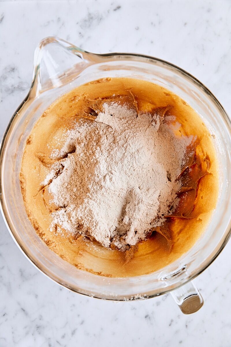 Dry ingredients added to ginger cookie dough in glass mixing bowl