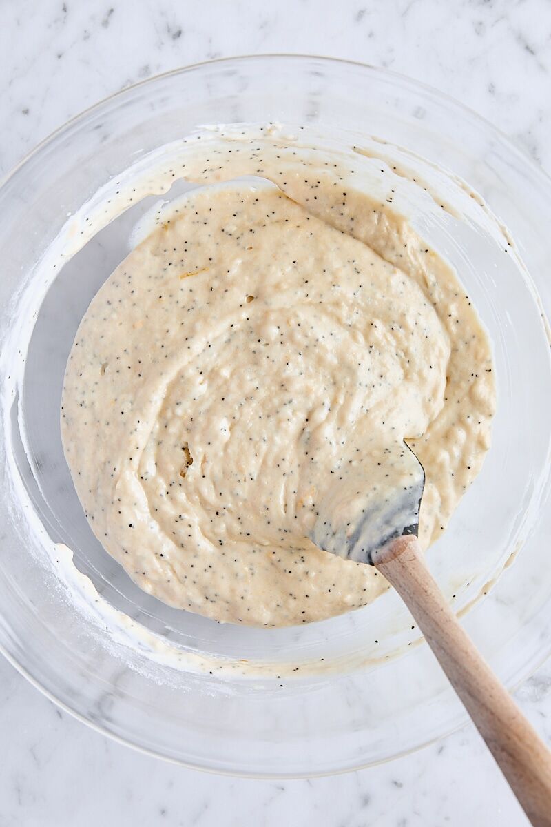 Lemon poppy seed muffin batter in large glass bowl with spatula