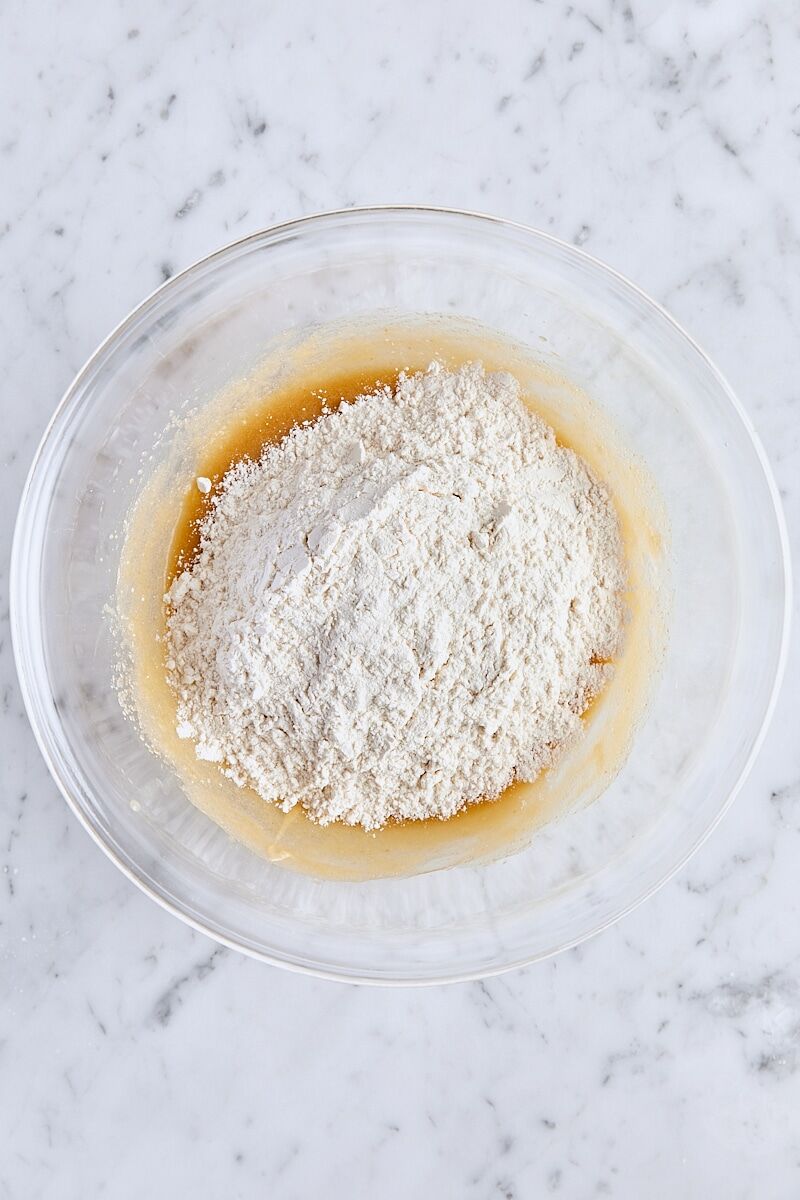 Flour mixture added to cookie dough in glass bowl