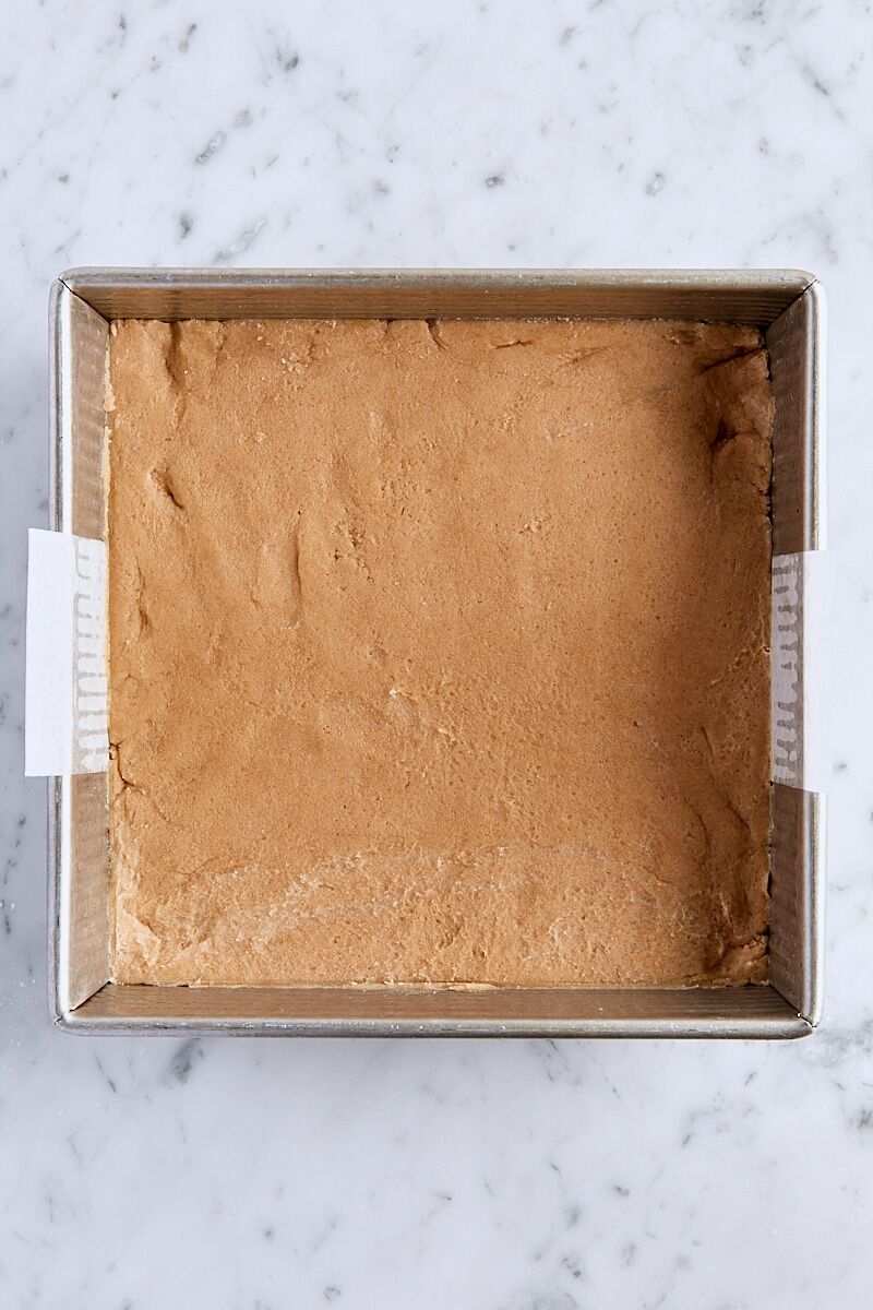 Snickerdoodle dough pressed into parchment-lined square baking pan