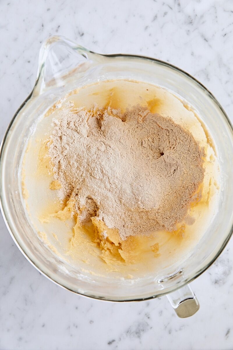 Flour mixture added to snickerdoodle dough in glass mixing bowl