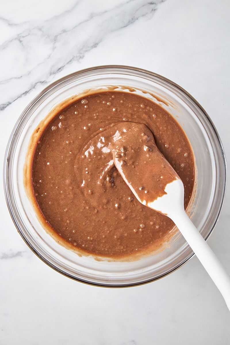 Chocolate donut batter in glass bowl with spatula