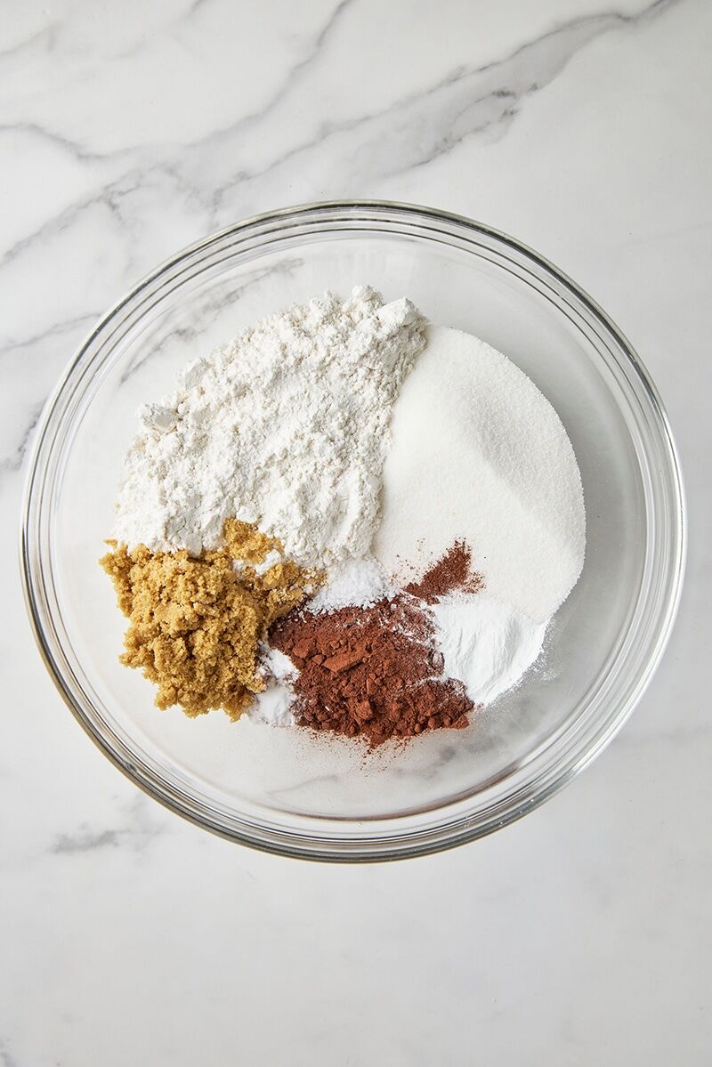 Cake flour, cocoa, granulated sugar, light brown sugar, baking powder, baking soda, and salt in glass bowl