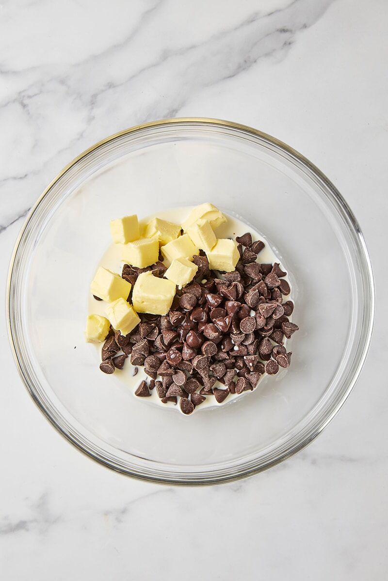 Semisweet chocolate chips, salt, heavy cream, and cubed butter in glass bowl