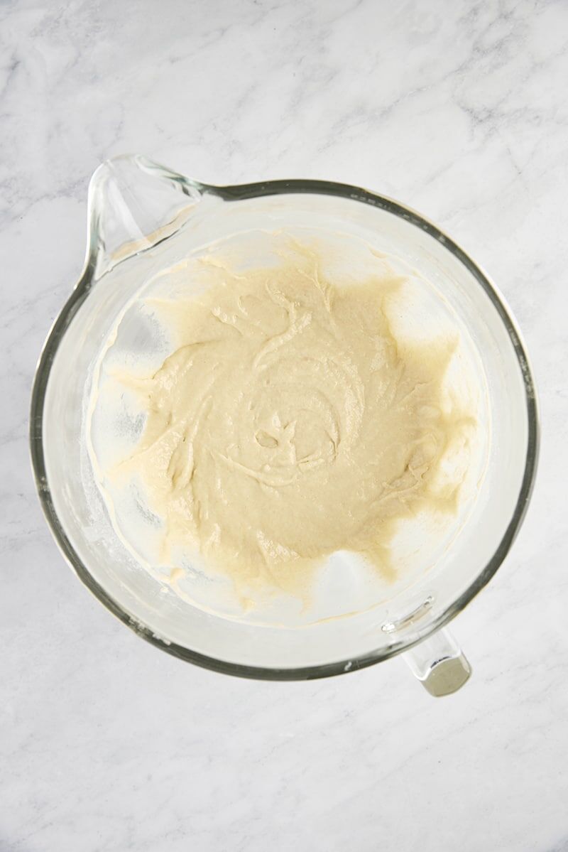 Wet ingredients mixed into dry ingredients in glass mixer bowl