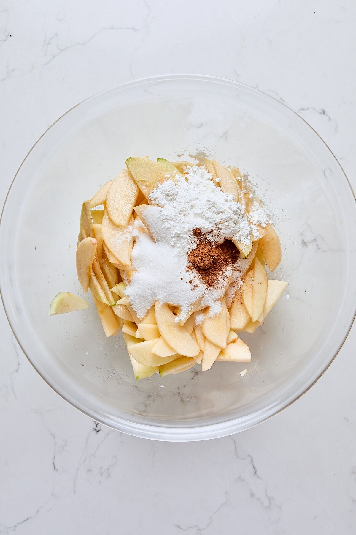 Granulated sugar, cornstarch, cinnamon, and salt added to bowl with sliced apples