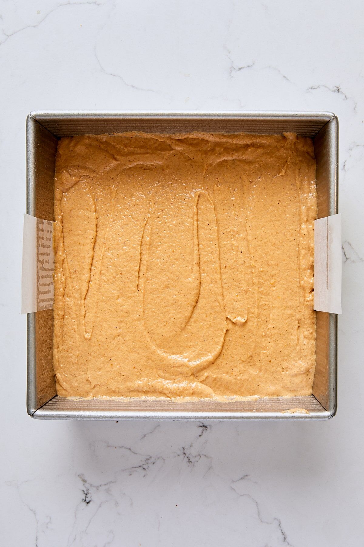 Pumpkin crumb cake batter in parchment-lined square pan